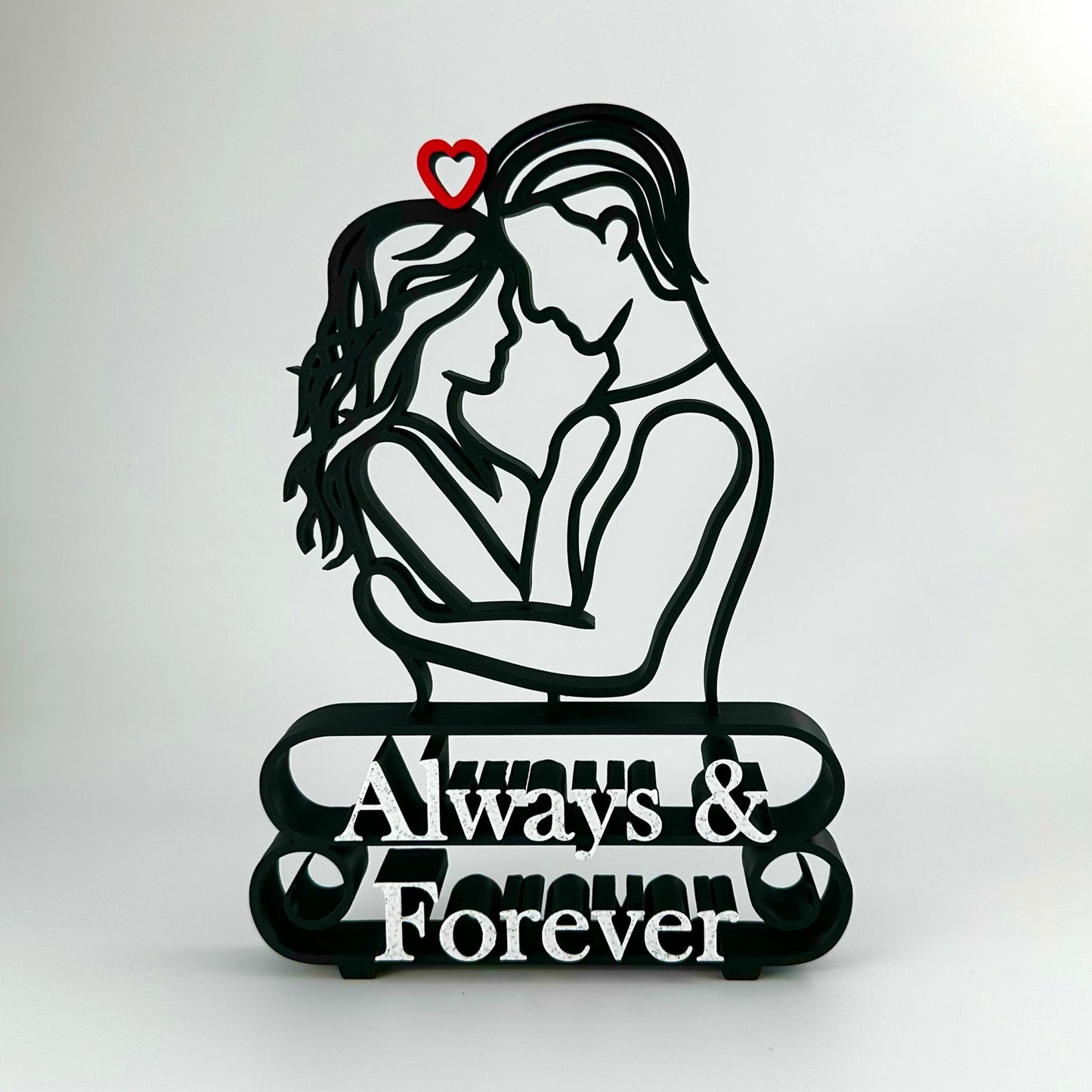 Decorative matte black plastic line art sculpture featuring a couple embracing, a red heart, and marble 'Always & Forever' text.