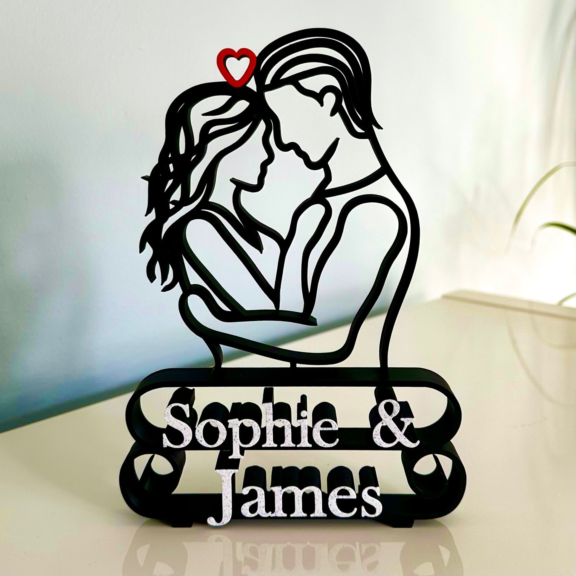 Decorative line art sculpture with a silhouette of a couple embracing and 'Sophie & James' marble effect text underneath.