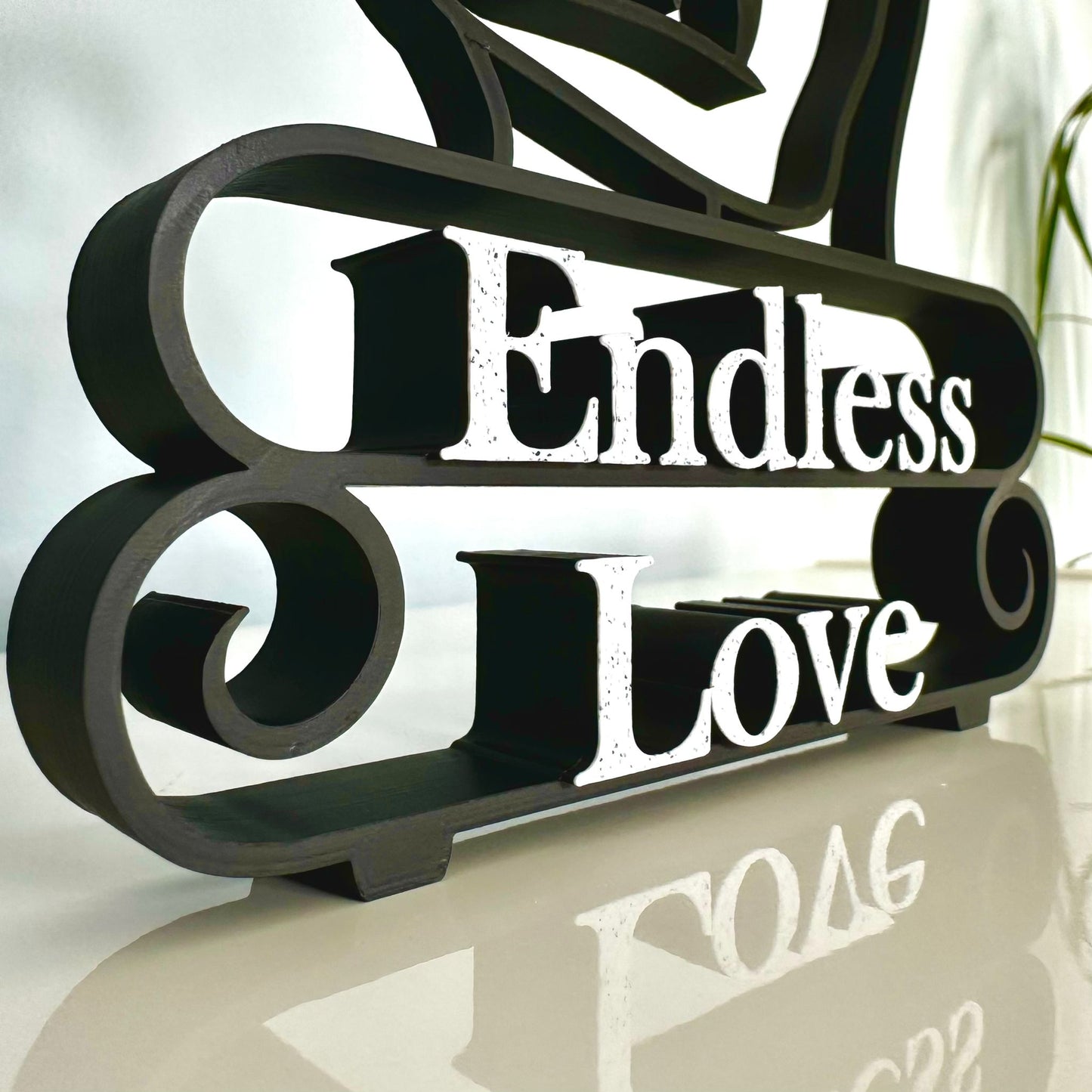 Matte black decorative statue with 'Endless Love' marble text on a reflective surface