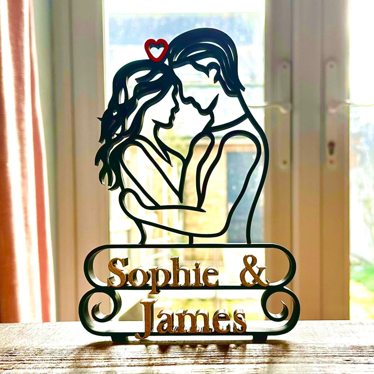 Gorgeous line art sculpture of a couple embracing and 'Sophie & James' marble effect text underneath, silhouetted against a window