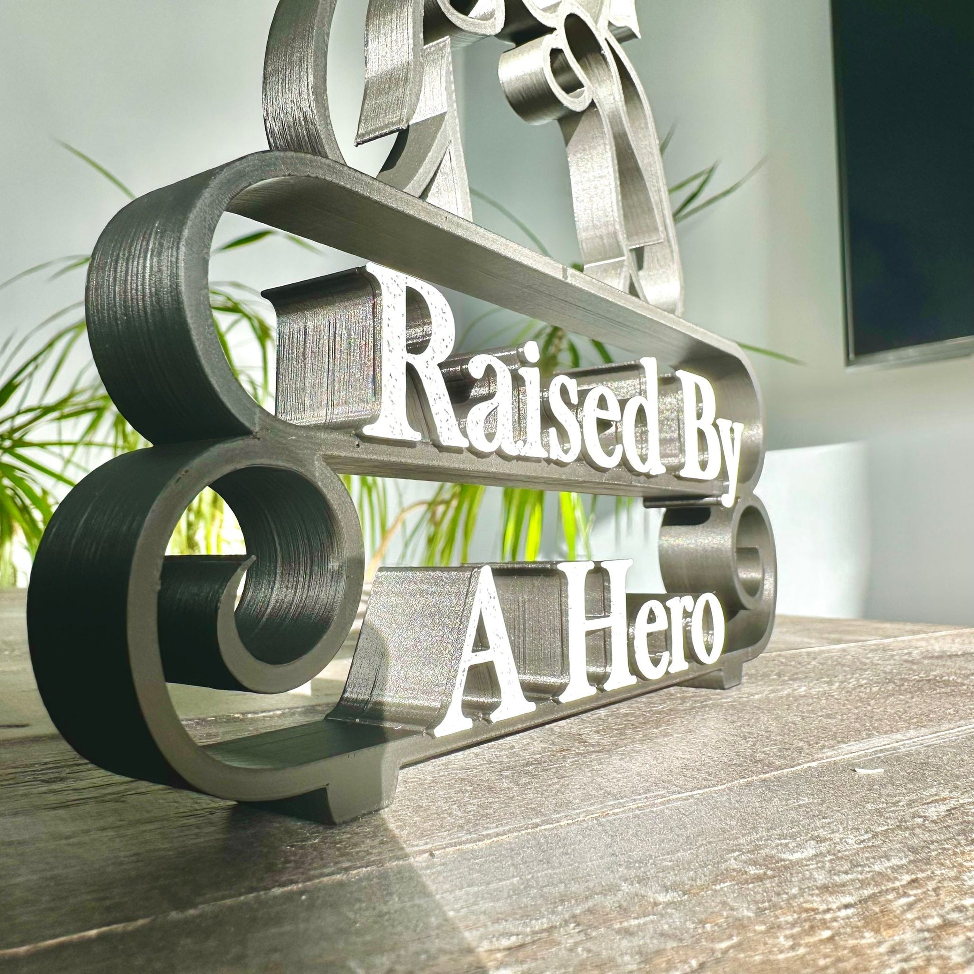 Modern plastic line art sculpture - zoomed in on the text 'Raised By A Hero', 3D-sculpted.