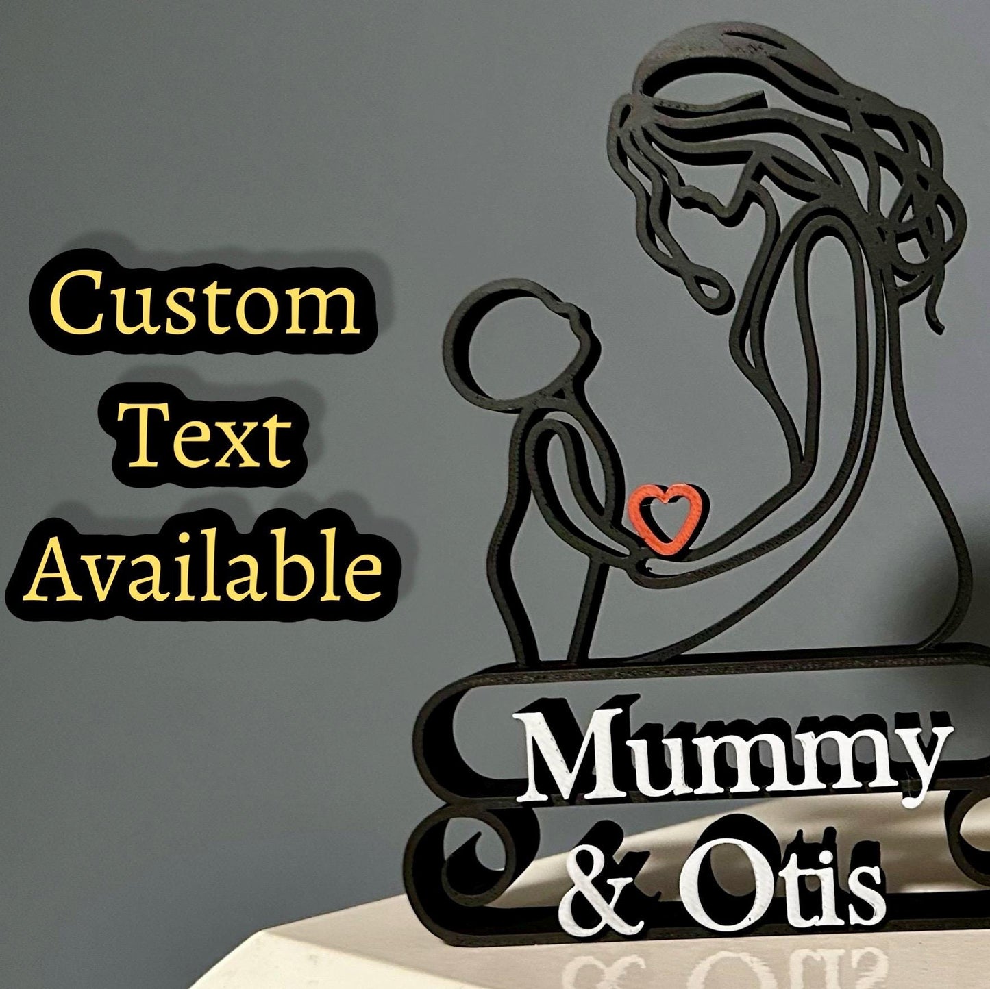 Line art sculpture of a mother holding a child, with a red heart and custom text on the base